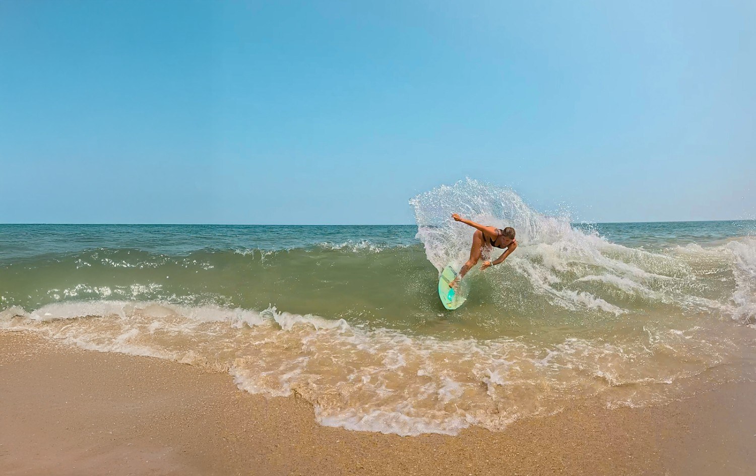 Persona practicando skimboard en la orilla al atardecer.
